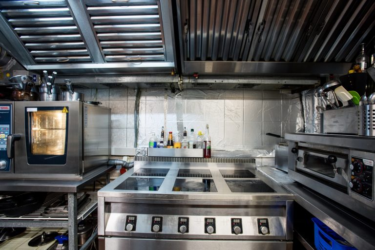 Part of interior of modern restaurant kitchen including electric stove and oven