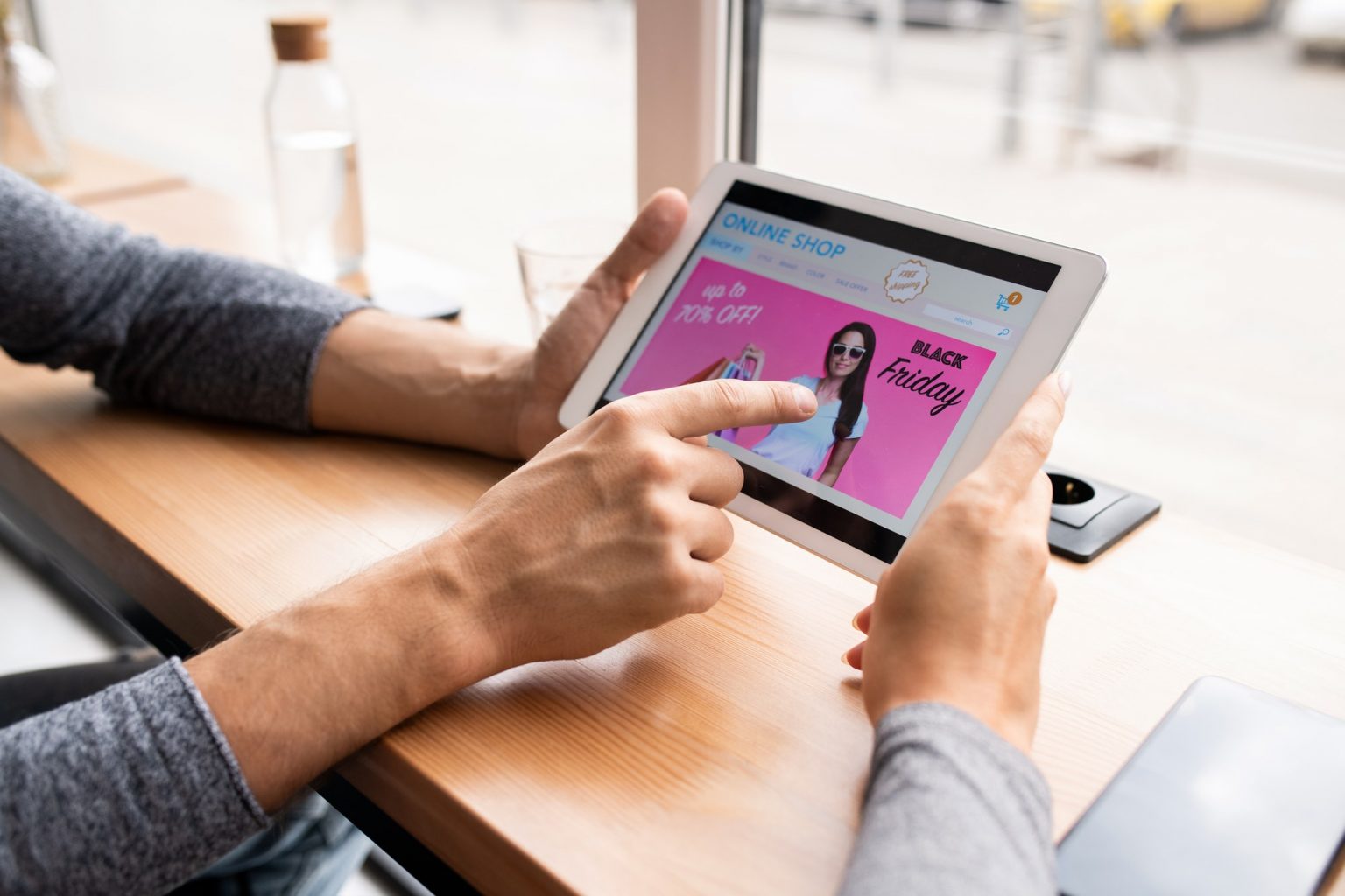 Young man holding touchpad and pointing at black friday sale screensaver